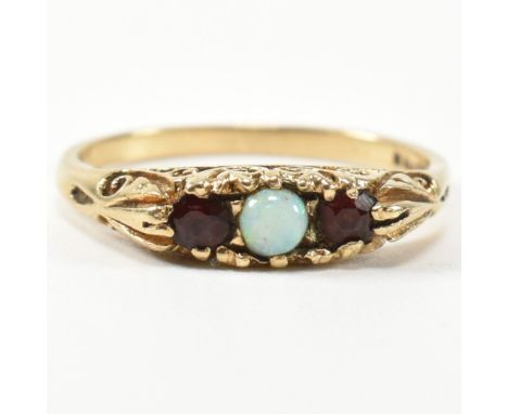 A 1940s hallmarked 9ct gold, opal and garnet three stone gypsy ring. The ring having a central round opal cabochon flanked by