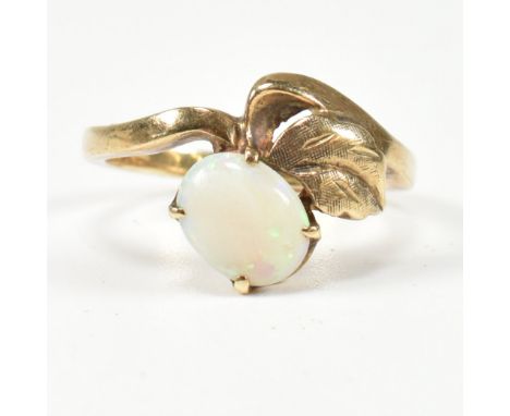 A 9ct and opal ring. The ring having a four claw set oval opal cabochon set surmounted above a gold leaf to give the appearan