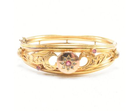A 19th century gold gem and diamond set hinged bangle. The bangle set with a central gem framed by a halo of rose cut diamond