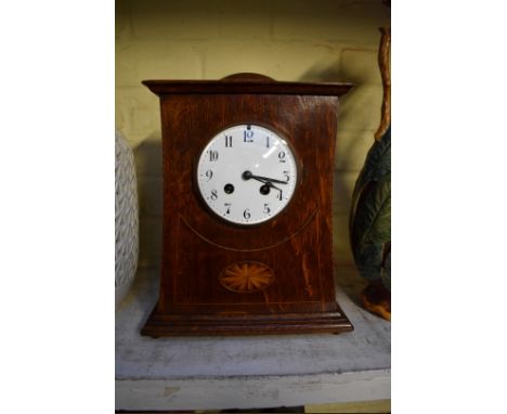 An Arts and Crafts style oak and inlaid mantel clock, with enamel dial, 30.5cm high, with pendulum.&nbsp; 