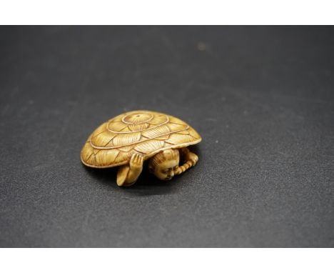 A Japanese carved ivory netsuke, Meiji, depicting a man crouching under a large straw hat, 4.3cm wide 