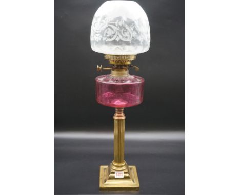 An antique brass oil lamp,&nbsp;with cranberry glass reservoir, height including shade 62cm.&nbsp;&nbsp; 