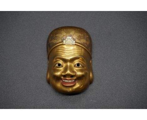 An extremely fine and unusual Japanese carved ivory, gilt lacquer and mother-of pearl Buddha mask netsuke or okimono, 19th ce