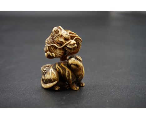 A good Japanese carved ivory netsuke or okimono, Edo, depicting a dragon and tiger, 5cm high. 