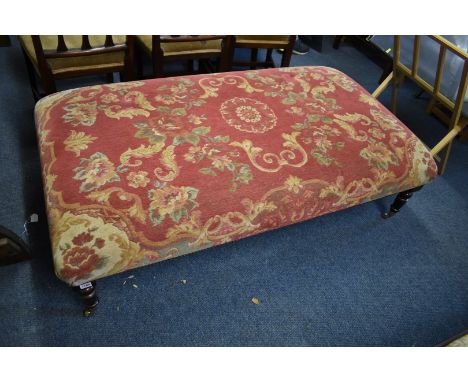 A large upholstered stool or pouffe,&nbsp;on stained beech legs with brass caps and casters, 147cm x 84cm.&nbsp; 