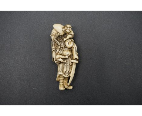 A good Japanese carved ivory netsuke, Edo, depicting a man with two demons, with standing figure with inset eyes, 7.5cm long.