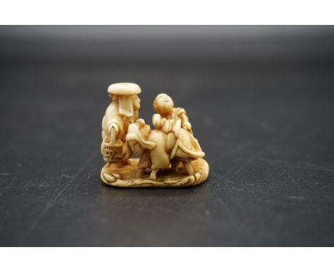 An unusual Japanese carved ivory netsuke, probably Edo, depicting a cow like woman, with man and child, signed, 2.8cm high. 