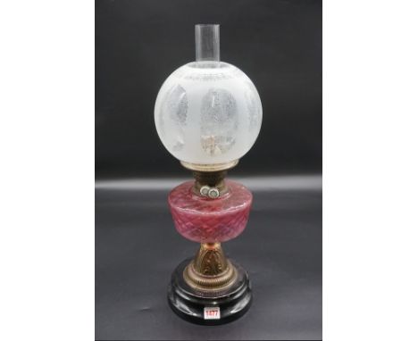 An antique brass oil lamp,&nbsp;with cranberry glass reservoir, height including shade 49.5cm, (chip to bottom rim of shade).