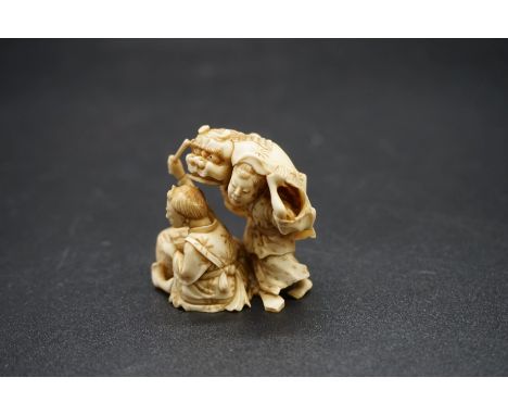 A good Japanese carved ivory netsuke, 19th century, depicting two figures with a tiger skin and drum, signed, 3.8cm high. 