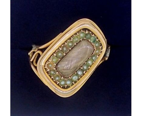 A Victorian gold mourning ring with diagonally set hair locket within seed pearl surround, unmarked, but tested as gold, size