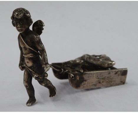 A small silver figure of a cherub and sled