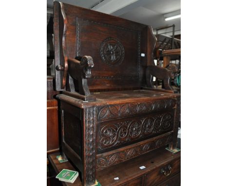 A 1920s carved and panelled oak monk's bench, width 90cm.