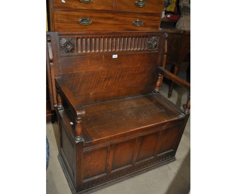 A 1920s carved and panelled oak monk's bench, width 100cm.
