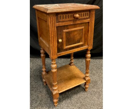 An early 20th century oak pot cupboard, rouge marble top, single short drawer to frieze, above a cupboard door, turned and fl