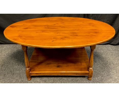 A 20th century oval yew coffee table, shelf under tier, turned supports, 53cm high, 120cm long, 83cm wide 