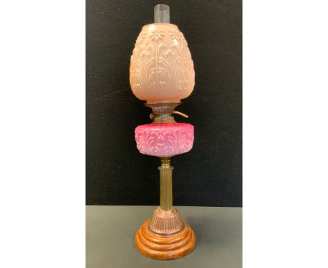 A Victorian oil lamp, pink milk glass reservoir, copper column, floral shade, wooden foot, 67cm high overall 