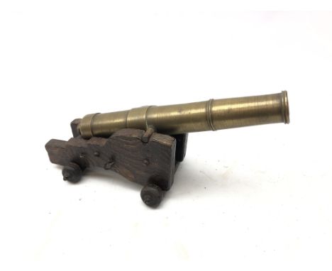 Brass model cannon, loose mounted on elm shaped carriage with carved wooden wheels L29cm Condition Report Click here for furt