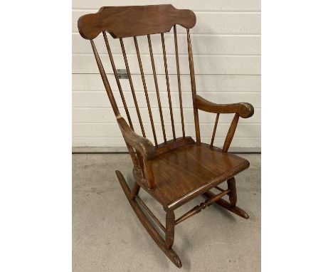 A vintage wooden spindle backed rocking chair with turned legs and supports. 