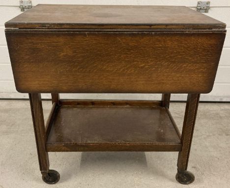 A vintage dark wood drop leaf tea trolley with under shelf. 