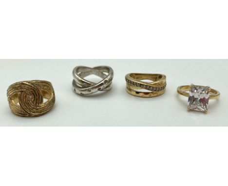 4 silver and silver gilt dress rings. 2 x cross over designs set with clear stones, an emerald cut clear stone solitaire styl