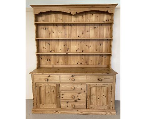 A large modern pine dresser with 6 drawers and 2 cupboards to base and 3 shelves to top. Shaped plinth to top and bun handles