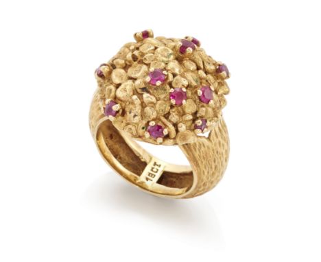 A ruby set cluster ring, the circular nugget style head with scattered claw set rubies, to tapering textured hoop, stamped 18
