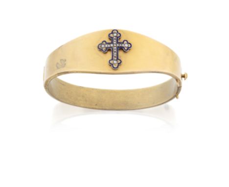 A Victorian gold hinged bangle, of hollow tapered design, with applied central enamel and half-pearl Latin cross to the centr