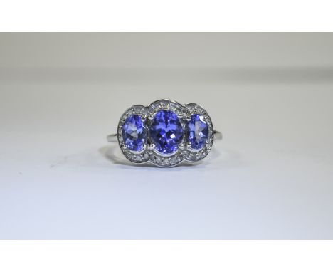 Tanzanite and Diamond Trilogy Ring, three oval cut tanzanites, of excellent colour, the central stone alone being 1ct, framed