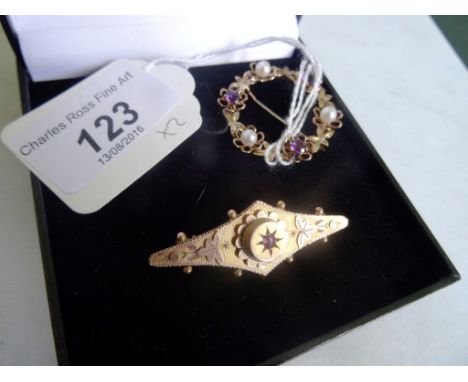 A 9 carat gold Edwardian brooch, inset with a ruby, together with a 9 carat gold pearl and amethyst circular brooch of foliat