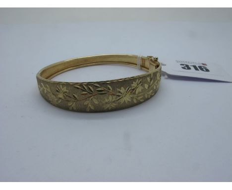 A Modern 9ct Gold Hinged Bangle, foliate engraved to the front, hinged to snap clasp (9grams).  