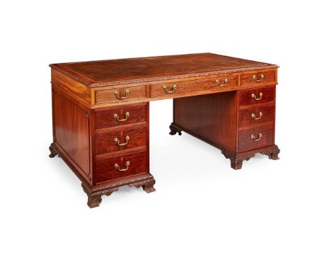 the brown leather insert top with a leaf carved edge over three frieze drawers and twin banks of three drawers, with a pair o