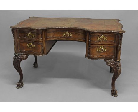 A MAHOGANY LEATHER-TOPPED WRITING DESK, in the Chippendale style, the shaped rectangular top with tooled leather inset and mo