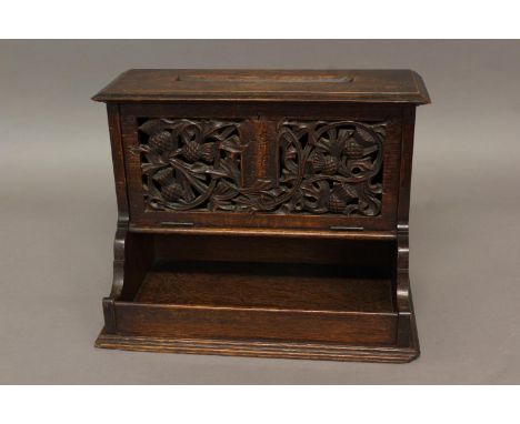 AN ARTS AND CRAFTS OAK COUNTRY HOUSE LETTER BOX, the rectangular top with pierced letter slot, above a hinged pierced and car