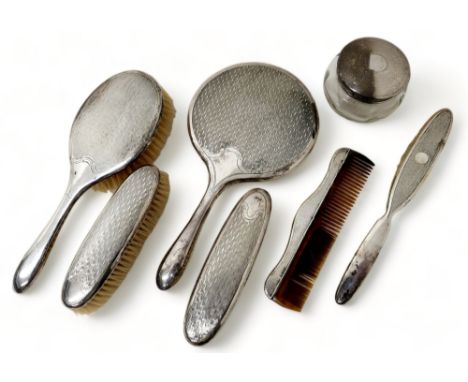 An Edwardian silver dressing table set comprising four brushes, tortoise shell comb, hand mirror and silver top glass jar.Bir