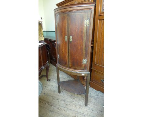 Georgian oak bow fronted storage cupboard on stand, original brass furniture, the lower portion inset on 3 plain feet inset o