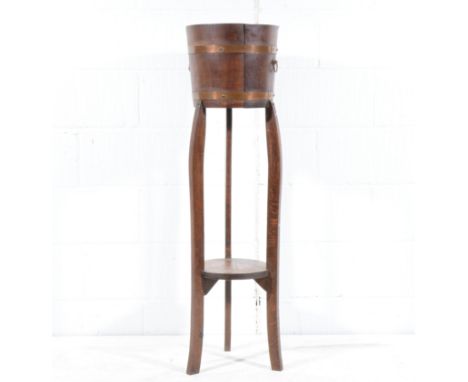 Oak jardiniere, cylindrical top with brass bands, legs joined by a shelf, height 119cm.