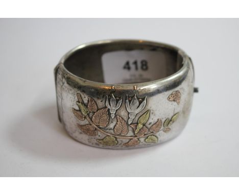 A silver colour metal bangle decorated in gold washed flowers and leaves 