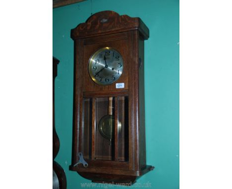 A 1920/30's Oak cased wall Clock having silvered metal dial with Arabic numerals, the pendulum visible through a bevelled gla