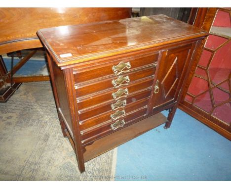 A circa 1930 Mahogany music Cabinet having six fall front, sheet music drawer, cupboard and a lower shelf, 31 1/4'' wide x 14