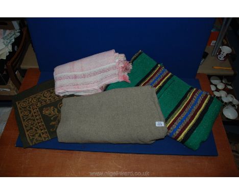 A heavy woven tablecloth, an Army blanket, a hand woven carpet green with stripes and a pink blanket.