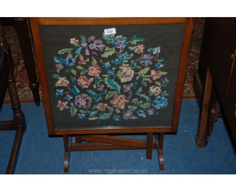 An Oak framed metamorphic Firescreen/Table, the panel decorated  with a hand worked tapestry, illustrating stylised flowers a