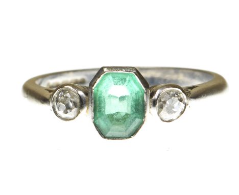 An emerald and diamond three stone ringThe step-cut emerald flanked by two old mine-cut diamonds, bezel set, to an 18k white 