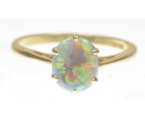 A black opal single stone ringThe oval cabochon opal, to a simple six claw setting, to an 18ct gold shank, opal weight 0.50ct