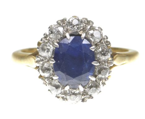 A sapphire and diamond cluster ringCentering an oval shape sapphire to an old-cut diamond surround, to an unmarked precious y