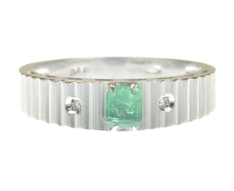 A modern emerald and diamond three stone ringCentering a step cut emerald flanked by two single-cut diamonds to a heavily rea