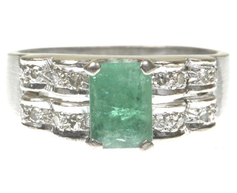 An emerald and diamond ringCentering a step-cut emerald to single-cut diamond scalloped shoulders, to precious white metal st