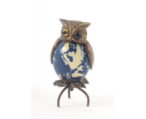A gilt brass and celluloid novelty tape measure, in the form of an owl, glass eyes, the complete but repaired tape wound from