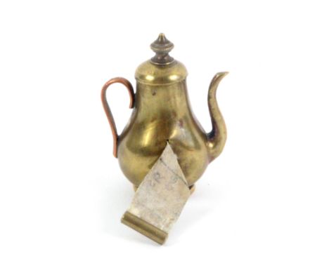 A copper and brass novelty tape measure in the form of a coffee pot, the complete printed tape in ins and cms, and wound from