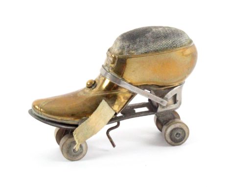 A novelty brass, white metal and wooden novelty tape measure/pin cushion in the form of a roller skate, with complete printed