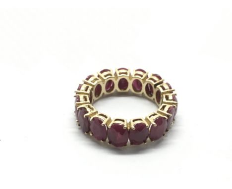 A yellow metal eternity ring set with red stones, possibly rubies, approx 7g and approx size Q-R.